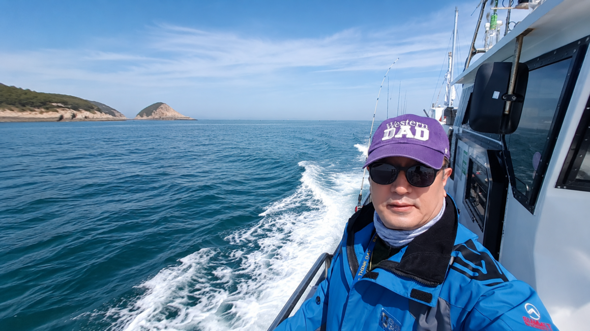 새벽 서해 바다 낚싯배 위에서 Western DAD 모자를 쓴 중년 낚시꾼의 셀카