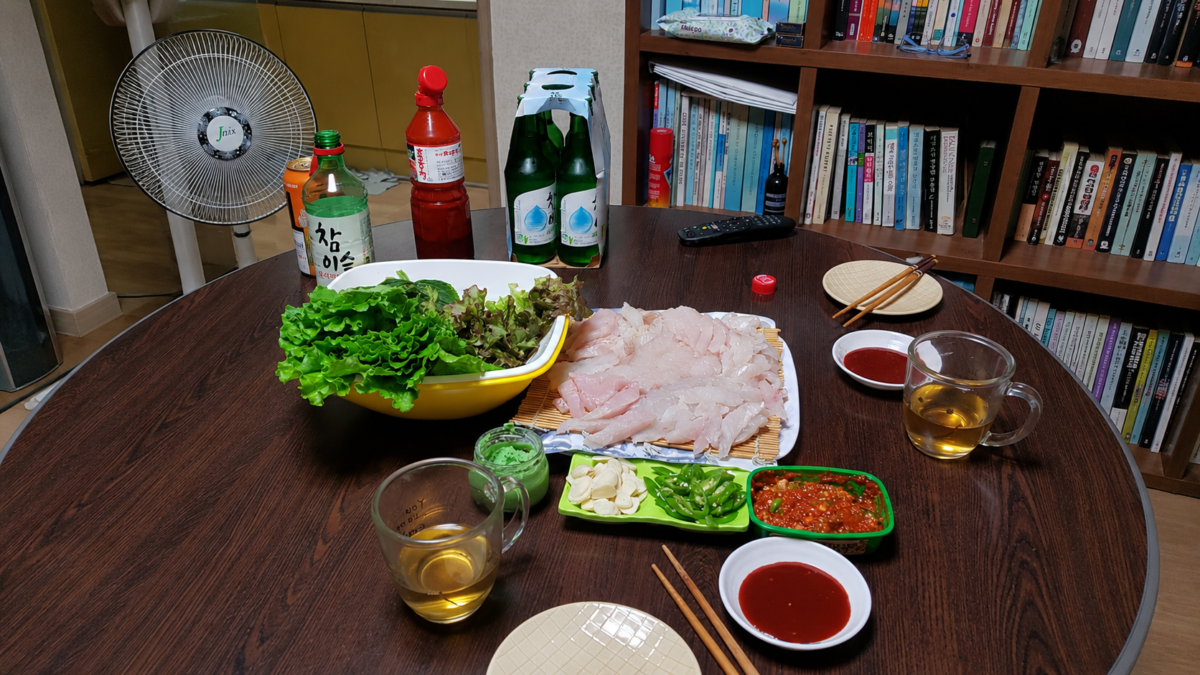 미국문학 책장 앞에 차린 직접 뜬 광어회와 상추, 소주 한 병